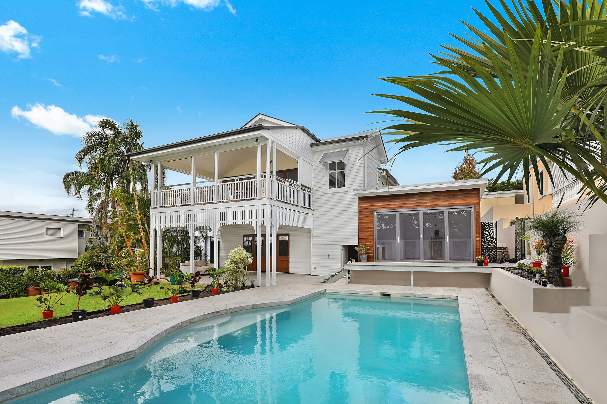 A bright two-story home with a pool and palm trees, sold and closed