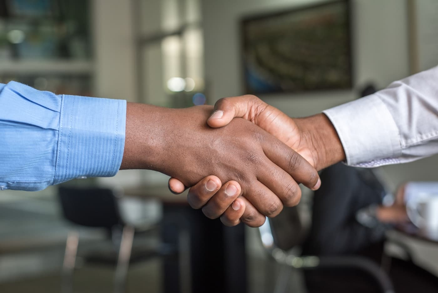 Two people shaking hands across a desk after agreeing on terms